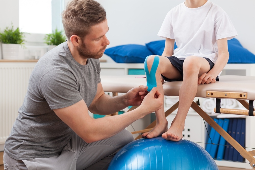 Physical therapist applying young patient medical tape